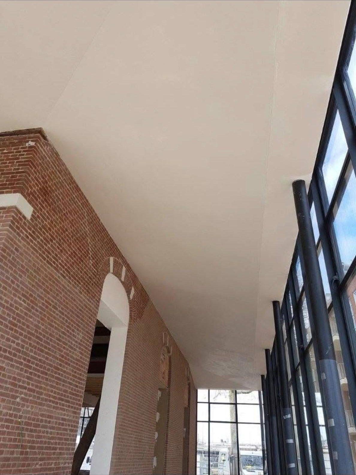 Plafond op zes meter hoogte, gestukadoord en afgewerkt met akoestisch spuitwerk