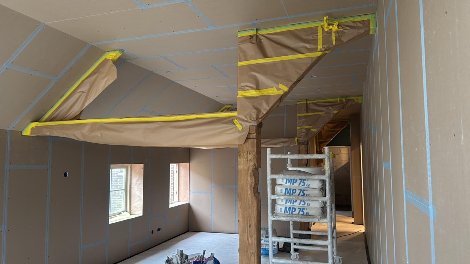 Ruimte met houten spanten volledig afgeplakt voor het stucwerk