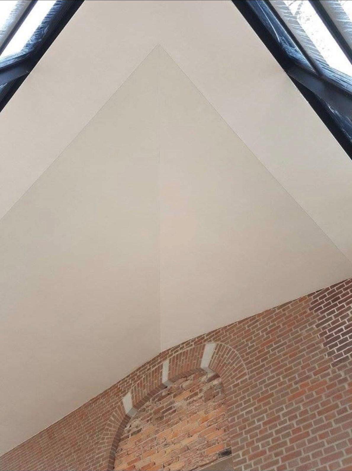Strak gestuct schuin plafond boven een bakstenen boog